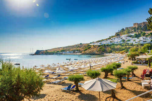 View of sandy beach in Bay of Lindos, Acropolis in background (R