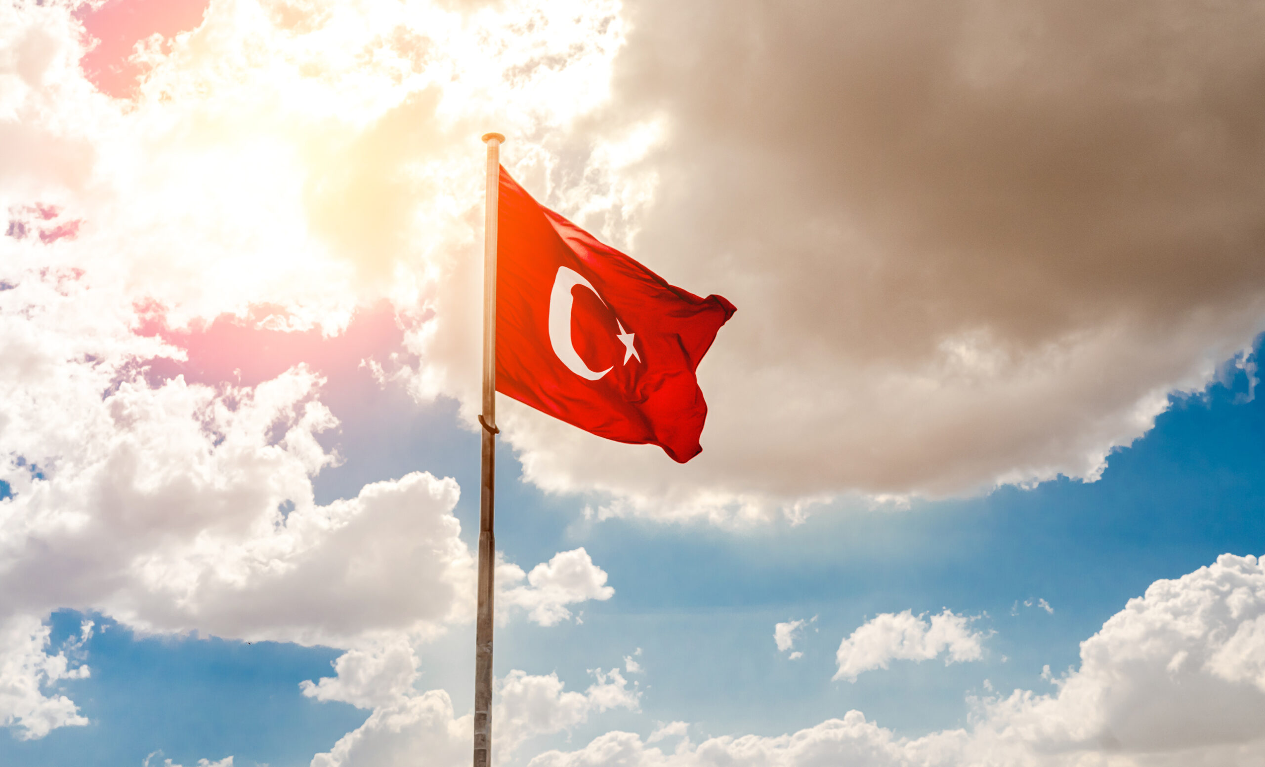 National flag of Turkey on pole waving in wind on cloudy sky background